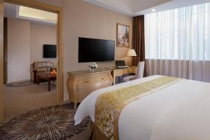 una camera d'albergo con letto e scrivania con TV di Vienna Hotel Guangzhou Baiyun Airport a Canton