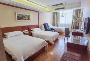 Vienna Hotel Nantong Tongzhou Bus Station tesisinde bir odada yatak veya yataklar