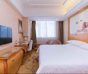 a hotel room with a bed and a television at Vienna Hotel Shenzhen Baoneng City Plaza in Longgang
