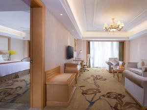 a hotel room with a bed and a living room at Vienna International Hotel Foshan Beijiao New City Meidi Headquarter in Shunde +3 photos