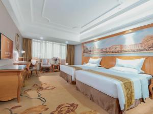 Guigang的住宿－維也納國際酒店廣西貴港荷城路店，酒店客房配有两张床和一张书桌