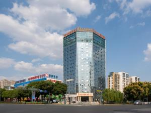 a tall glass building in front of a city at Vienna International Hotel Changzhou Hutang in Changzhou