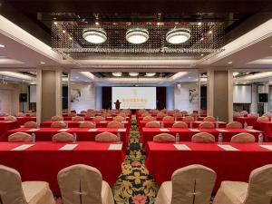 Vienna Hotel - Guangzhou South Railway Station Branch في قوانغتشو: قاعة اجتماعات بها طاولات وكراسي حمراء ومنضدة
