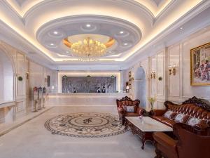 a living room with a chandelier and a couch and a table at Vienna International Hotel Shenzhen Caopu Jindaotian in Shenzhen +1 photo