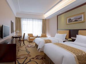 a hotel room with three beds and a television at Vienna Hotel Dongguan Changping Avenue in Dongguan