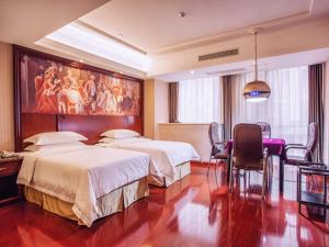 a hotel room with two beds and a painting on the wall at Vienna Hotel Jiangxi Yingtan International Glasses City in Yingtan