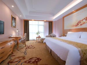 Habitación de hotel con cama grande y escritorio. en Vienna Hotel Guangdong Maoming Railway Station, en Maoming