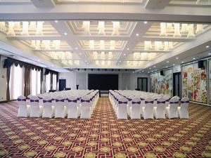 a banquet hall with rows of chairs and a screen at Vienna Hotel Yinchuan Railway Station in Yinchuan