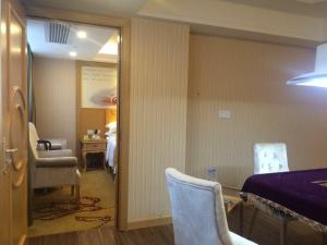 a room with a bed and a chair and a table at Vienna Hotel Meizhou Xingning District Plaza in Libei