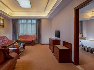 a hotel room with a bedroom and a living room at Vienna Hotel Guangzhou Airport 2 in Guangzhou