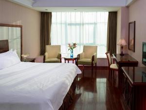 Pokój hotelowy z łóżkiem, biurkiem i krzesłami w obiekcie Vienna Hotel Shenzhen Yousong Branch w mieście Bao'an