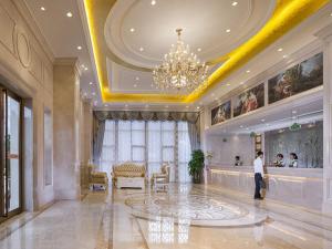 een man in een grote lobby met een kroonluchter bij Vienna Hotel Dongguan Chengcaiyuan International Plaza in Dongguan