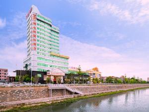 a tall building next to a body of water at Vienna Hotel Dongguan Hengli Zhongshan Road in Hengli