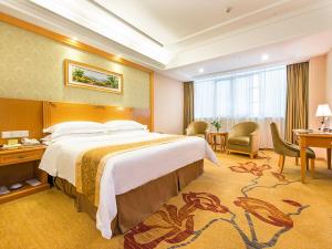 宝安にあるVienna Hotel Shenzhen View Lake Parkの大きなベッドとデスクが備わるホテルルームです。