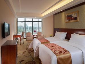 a hotel room with two beds and a desk at Vienna Hotel Shunde Longjia Exhibition Center in Shunde