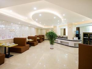um lobby com uma sala de espera com sofás e uma planta em Vienna Hotel Huizhou Railway Station em Huizhou