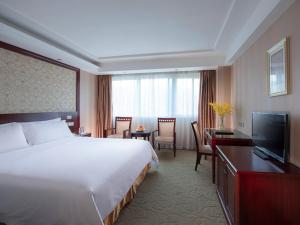 ein Hotelzimmer mit einem großen Bett und einem Flachbild-TV in der Unterkunft Vienna Hotel Shenzhen Fenghuang Road in Shenzhen