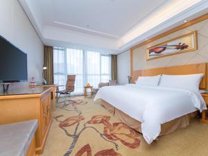 um quarto de hotel com uma cama grande e uma televisão de ecrã plano em Vienna Hotel Hubei Xiangyang Tanxi Road em Xiangyang