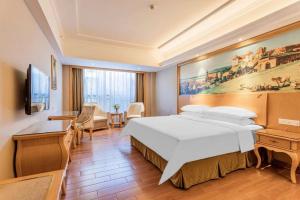 a hotel room with a large bed and a desk at Vienna Hotel Foshan Airport in Foshan