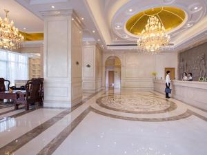 a woman standing in a large lobby with a chandelier at Vienna International Hotel Foshan Beijiao New City Meidi Headquarter in Shunde