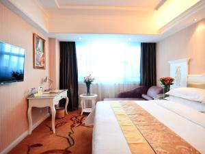 una camera d'albergo con un grande letto e una scrivania di Vienna Hotel Guangxi Guilin a Guilin