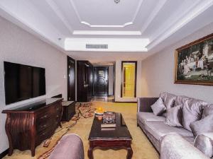 a living room with a couch and a flat screen tv at Vienna International Hotel Huizhou Huidong Honghaiwan in Huidong +4 photos