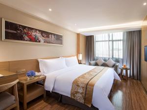 a hotel room with a large bed and a desk at Vienna 3 Best Hotel Shenzhen Pinghu Fumin Road in Longgang