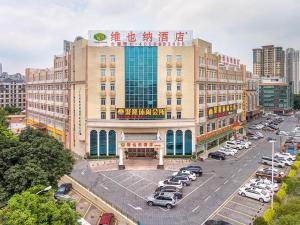 un grande edificio con auto parcheggiate in un parcheggio di Vienna Hotel Shiqiao Metro Station a Canton