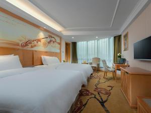 ein Hotelzimmer mit einem großen Bett und einem TV in der Unterkunft Vienna Classic hotel(Lianzhou Building Branch) in Lianzhou