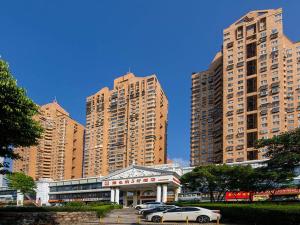 a group of tall buildings with cars parked in front at Vienna Hotel Shenzhen Shuiku New Village in Shenzhen