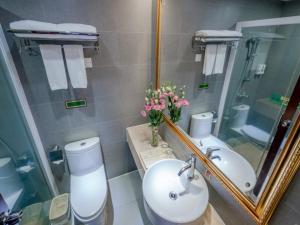 a bathroom with a sink and a toilet and a mirror at Vienna Hotel Guangzhou Shaheding Metro Station in Guangzhou