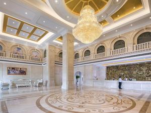 een grote lobby met een kroonluchter en een persoon die er in staat bij Vienna International Hotel Changsha Shumuling Subway Station in Changsha
