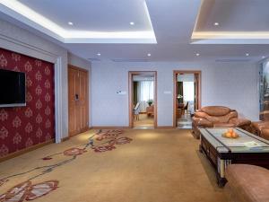 ein Wohnzimmer mit einem Sofa und einem TV in der Unterkunft Vienna Classic Hotel (Anlu Hengkun) in Zhulin