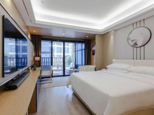 Schlafzimmer mit einem großen weißen Bett und einem Schreibtisch in der Unterkunft Vienna Hotel (Mulian West Road Shop, Changsha) in Changsha