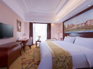 a hotel room with a large bed and a flat screen tv at Vienna Hotel Guangdong Gaozhou City East Passenger Depot in Gaozhou