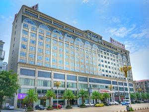 un gran edificio con coches estacionados frente a él en Vienna Hotel Guangxi Liuzhou Luzhai, en Luzhai