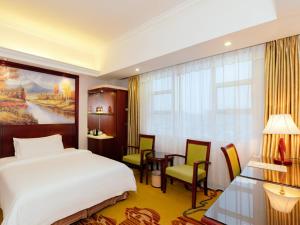 une chambre d'hôtel avec un lit, une table et des chaises dans l'établissement Vienna Hotel Huizhou Huiyang Danshui Road, à Huizhou