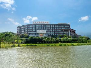 un gran edificio junto a una masa de agua en Vienna International Hotel Luogang Wanda Plaza, en Guangzhou