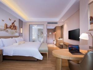 a hotel room with a bed and a desk with a laptop at Vienna International Hotel Nanjing Hehai University Station in Zhucun