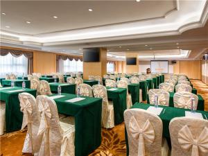 una sala de conferencias con mesas verdes y sillas en Vienna International Hotel (Shen Zhen Buji Dafen shop) en Shenzhen