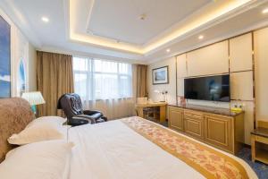 西寧市にあるVienna International Hotel Qinghai Xining Tianjun Bridgeのベッドとテレビが備わるホテルルームです。