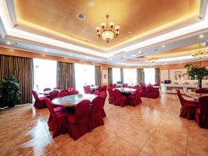 a large room with red chairs and tables and a chandelier at Vienna Hotel Changsha Jingwanzi Middle Mulian Road in Changsha