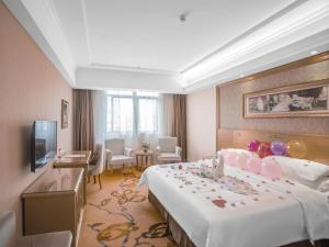 um quarto de hotel com uma cama grande e uma televisão em Vienna Hotel Shenzhen Buji Ganli Road em Longgang
