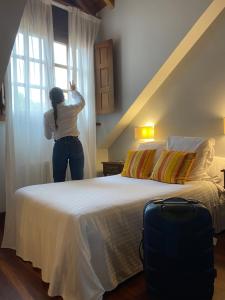 a woman standing next to a bed looking out the window at Don Pablo in Pechón