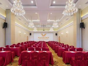 a large banquet hall with red clothed tables and chandeliers at Vienna Hotel (Huizhou Daya Bay Xinyi Store) in Huizhou