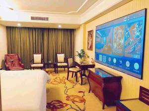 a hotel room with a large screen television and chairs at Vienna Hotel Guangzhou Shiling in Huadu