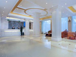 Ein Mann steht in einem großen Raum mit Lobby. in der Unterkunft Vienna Classic Hotel (Anlu Hengkun) in Zhulin
