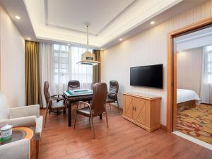a living room with a table and a room with a bed at Vienna Hotel Hunan Xincheng Guoji in Liuyang