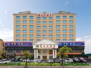 un grand bâtiment avec un kiosque dans un parking dans l'établissement Vienna Hotel Zhongkai Road Branch, à Huizhou
