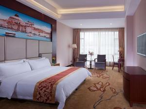 a hotel room with a large bed and a desk at Vienna Hotel Dongguan Hou Avenue Jinzuo in Hetian